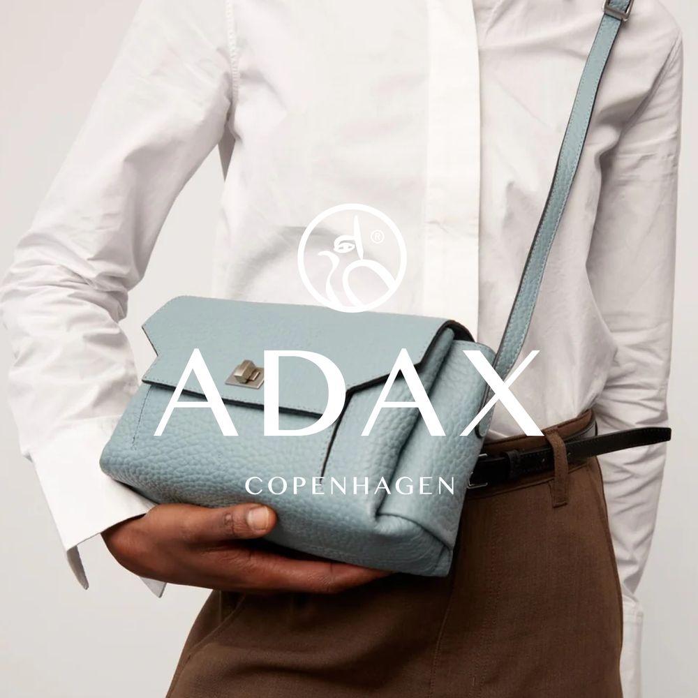 lyseblå skinn veske fra Adax, holdt av dame i vit skjorte