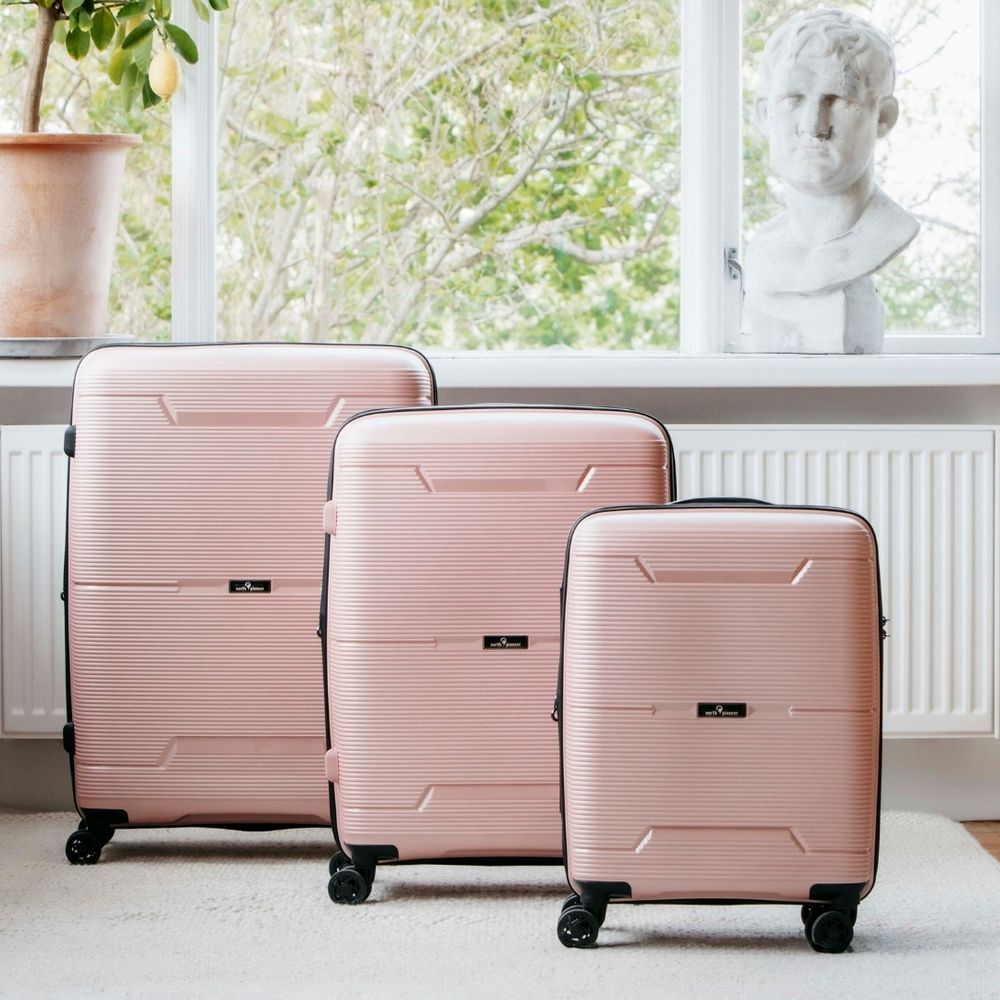 Rosa kofferter i tre størrelser i en lys stue 