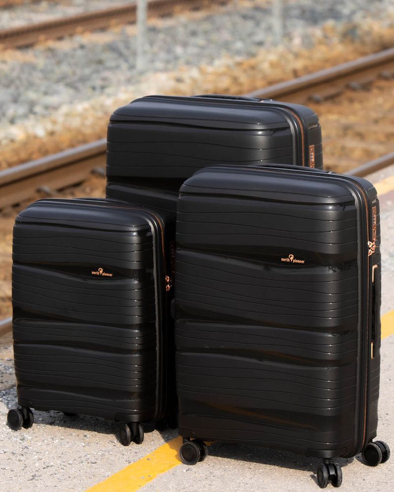 tre sorte kofferter på en togstasjon