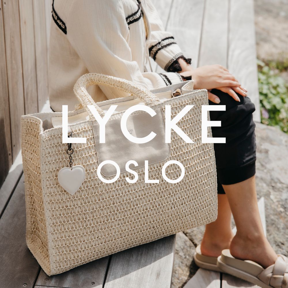 Lycke beige toteveske ved siden av dame som ser på utsikt over havet