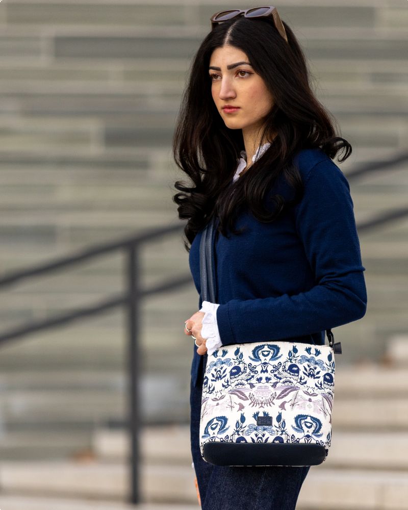 Dame i mørkeblå klær med en lys veske i stoff med mønster