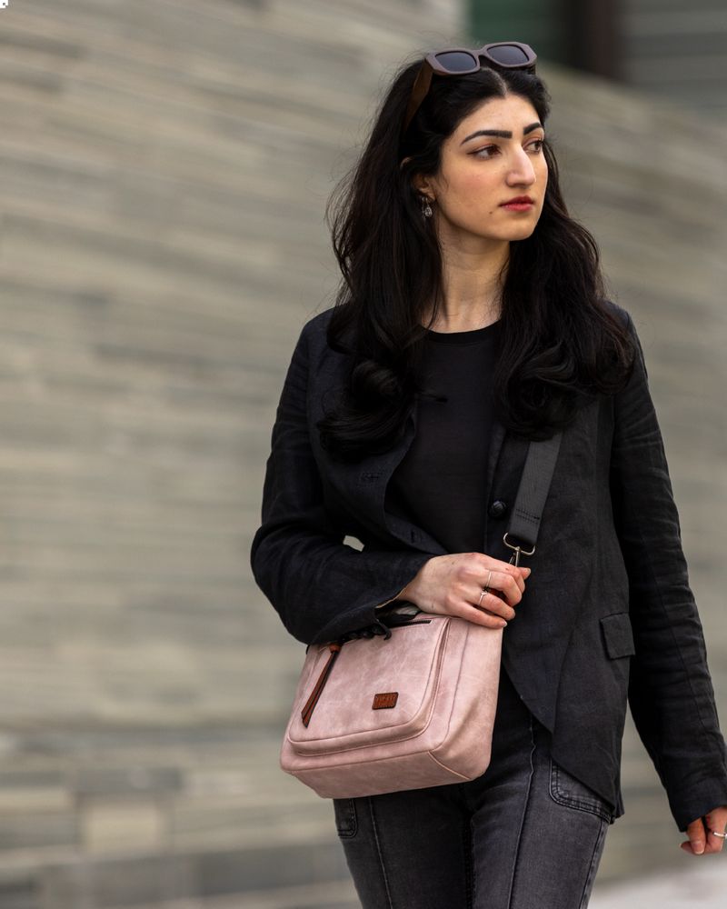 Dame i sorte klær med en lys rosa veske.