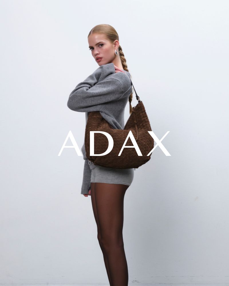 Kvinne med blondt hår, grå genser og brun danskdesignet skinnveske fra Adax