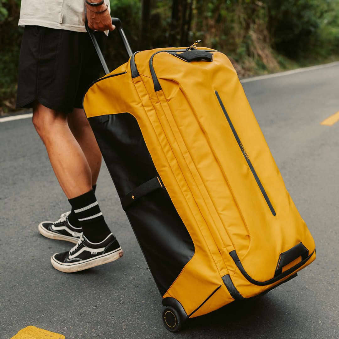 Reisebag med hjul trukket langs vei utendørs