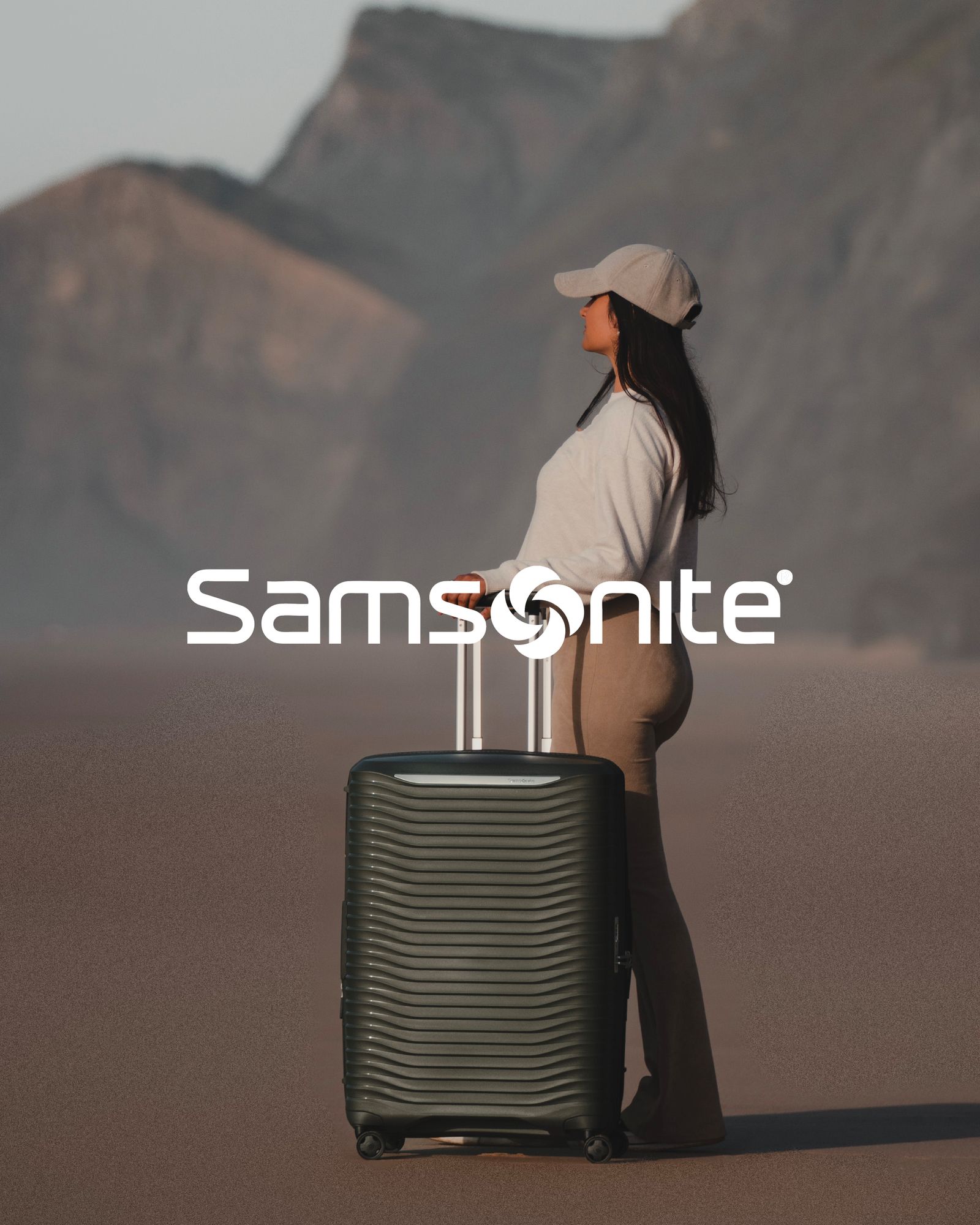 Dame med trillekoffert står i fjellandskap utendørs, samsonite logo