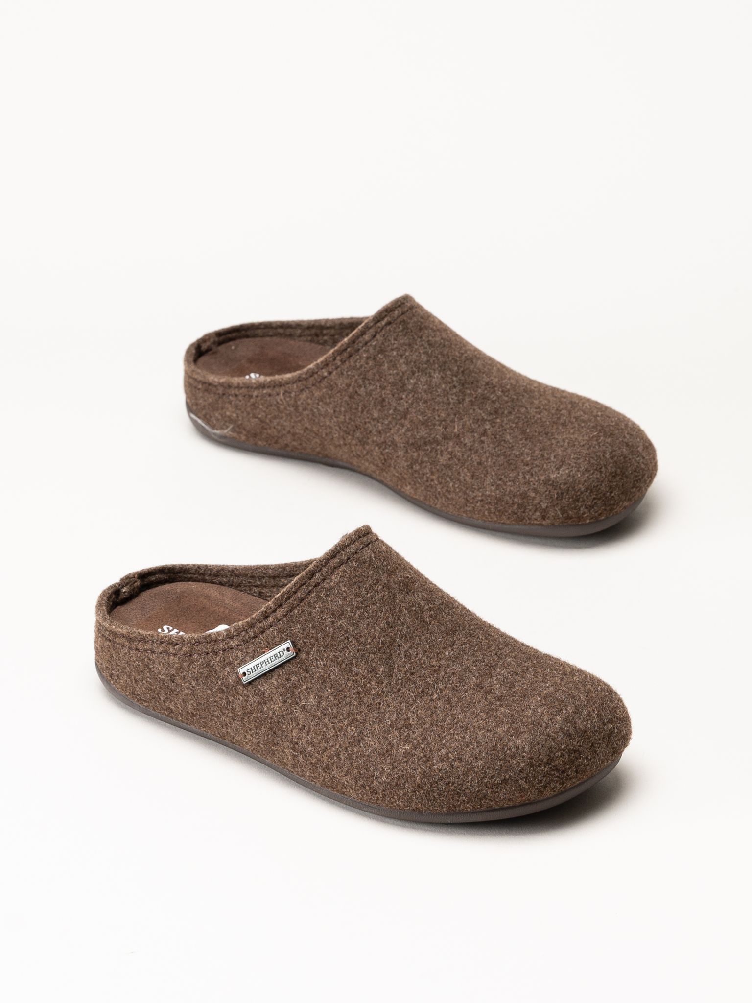 Bruna slip-on-tofflor i ull med stängd tå och öppen häl.