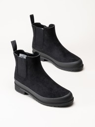 Ett par svarta Chelsea-boots i mocka med dragöglor och gummisulor