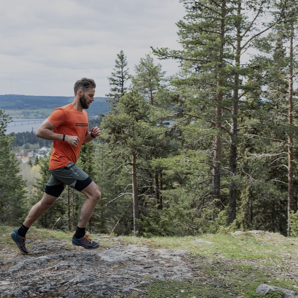 En kille som springer i naturen med swedemount kläder