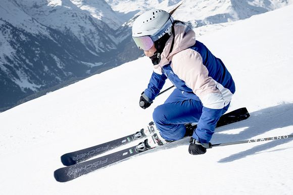 En tjej åker alpint ner för en skidbacke med bra skidor ifrån Fischer