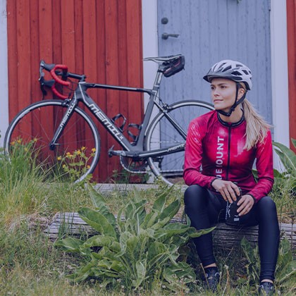 En kvinna med cykel vid ett hus