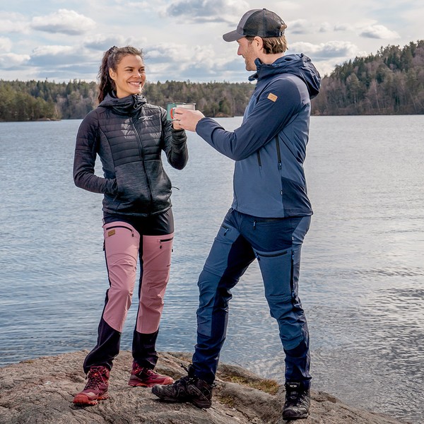 mies ja nainen seisovat järven rannalla Swedemountin retkeilyvaatteet päällä