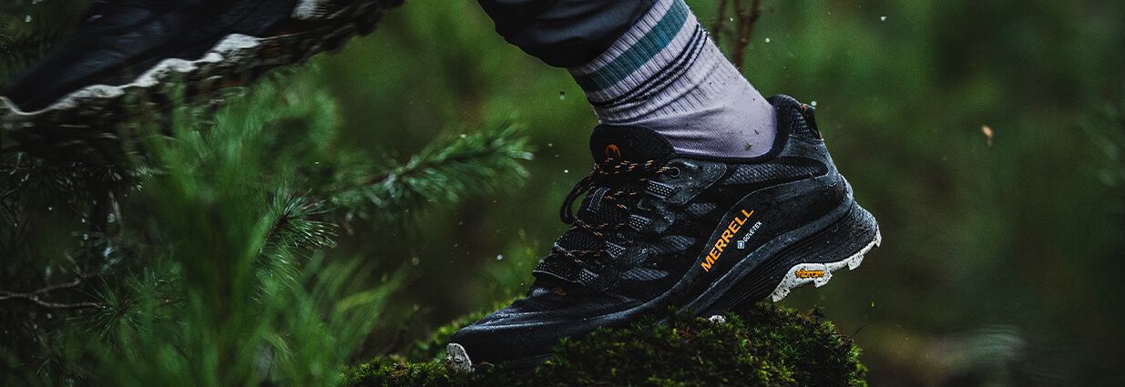 En svart merrell-sko i en våt skog