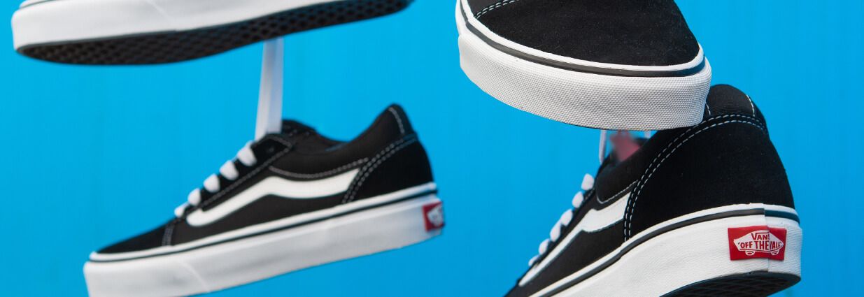 Svarta Vans sneakers med vita detaljer och blåbakgrund