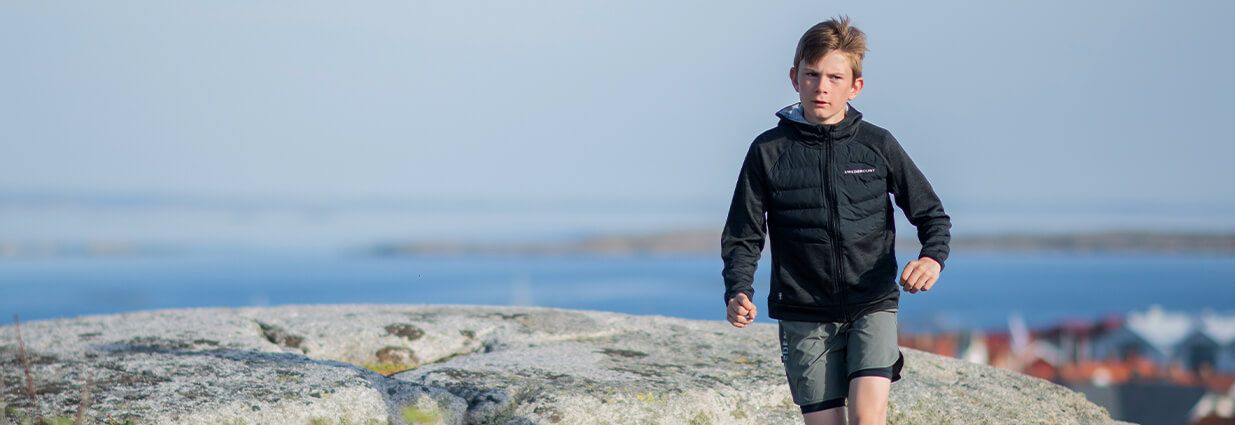 Ett barn/ junior som är ute och löper med löpkläder och shorts ifrån Swedemount