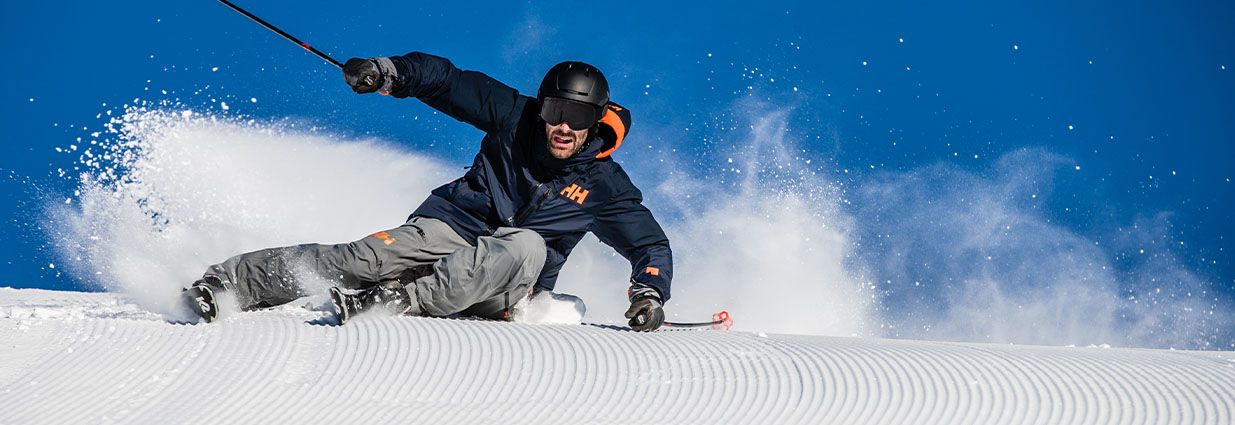 En fyr på ski ned en skiløype i skiklær fra Helly Hansen