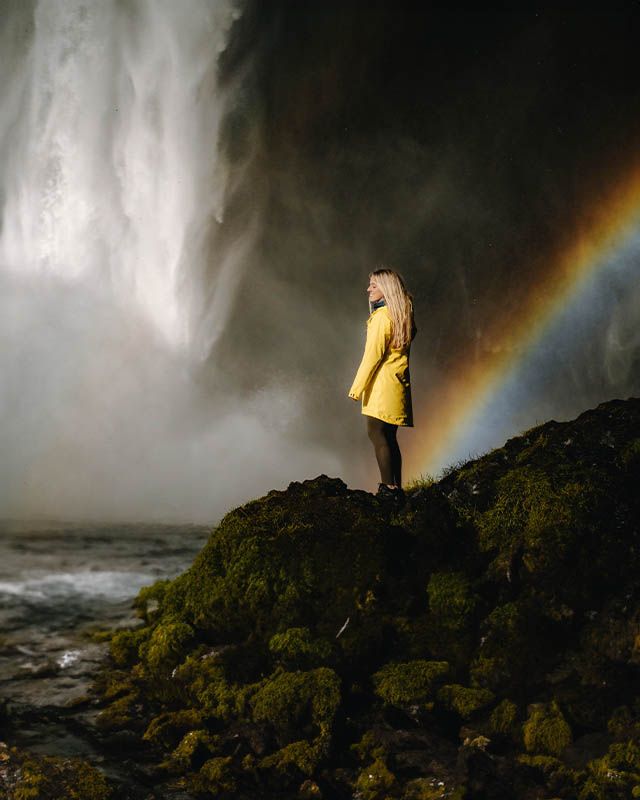 kvinna står vid vattenfall med en regnjacka