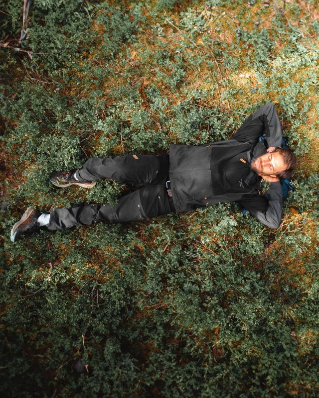 en man ligger i blåbärsriset med friluftskläder från Swedemount