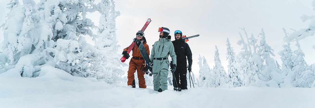 Två tjejer och en kille som går i snön med overaller från Swedemount