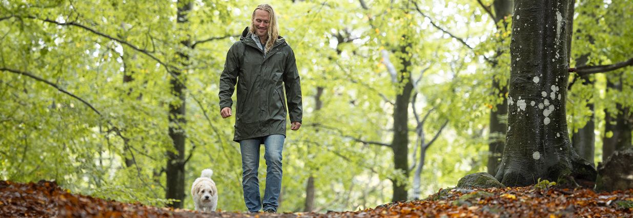 En kille går ute med en grå regnjacka ifrån Swedemount med vit tryck på bröstet