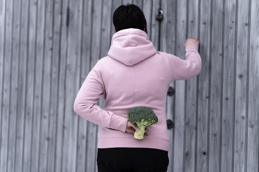 Woman holding a broccoli behind her back