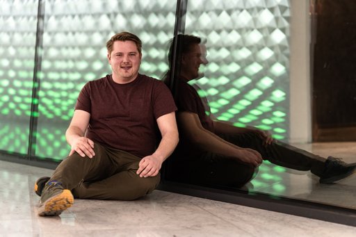 man leaning glass wall smiling