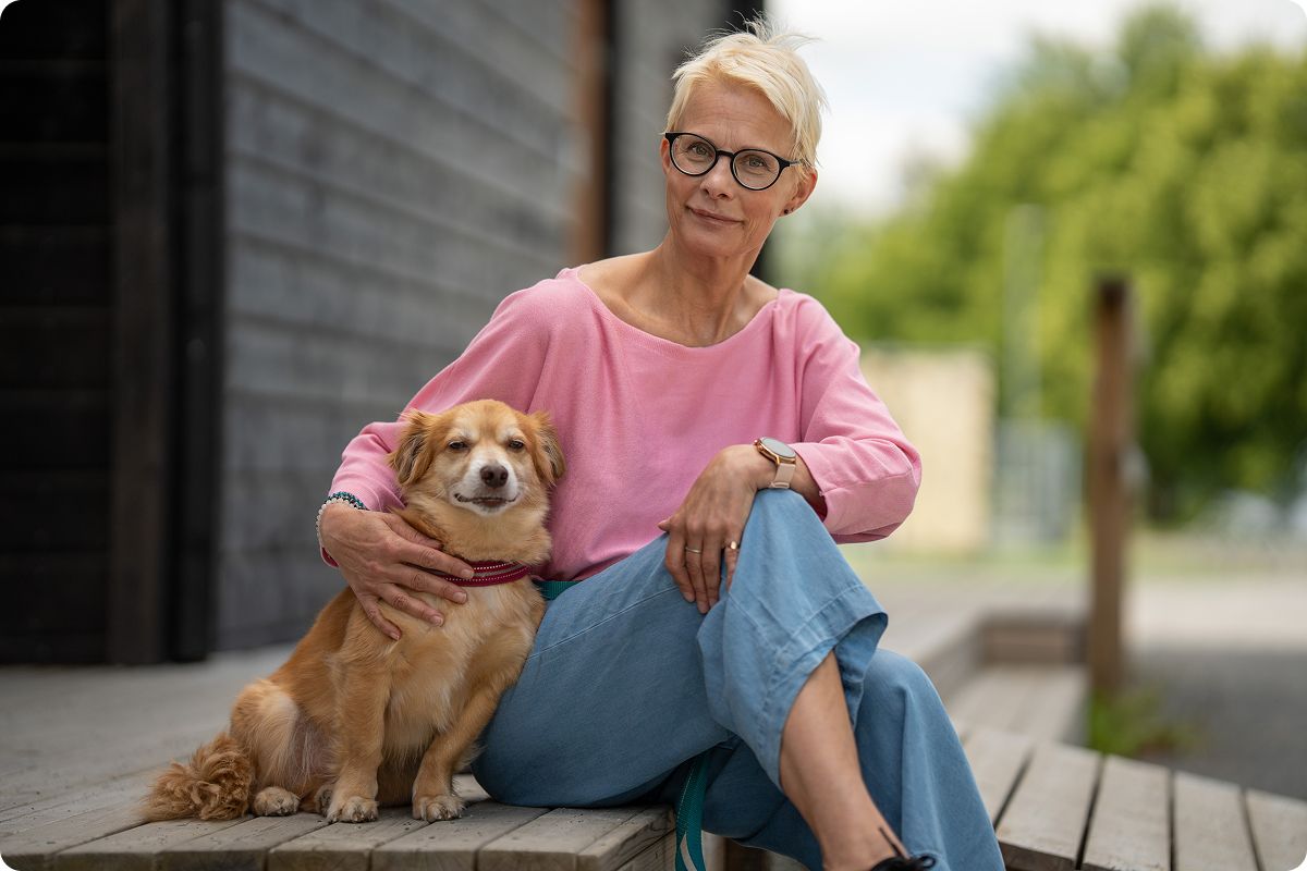 Older woman with glasses sitting on a porch with a golden dog