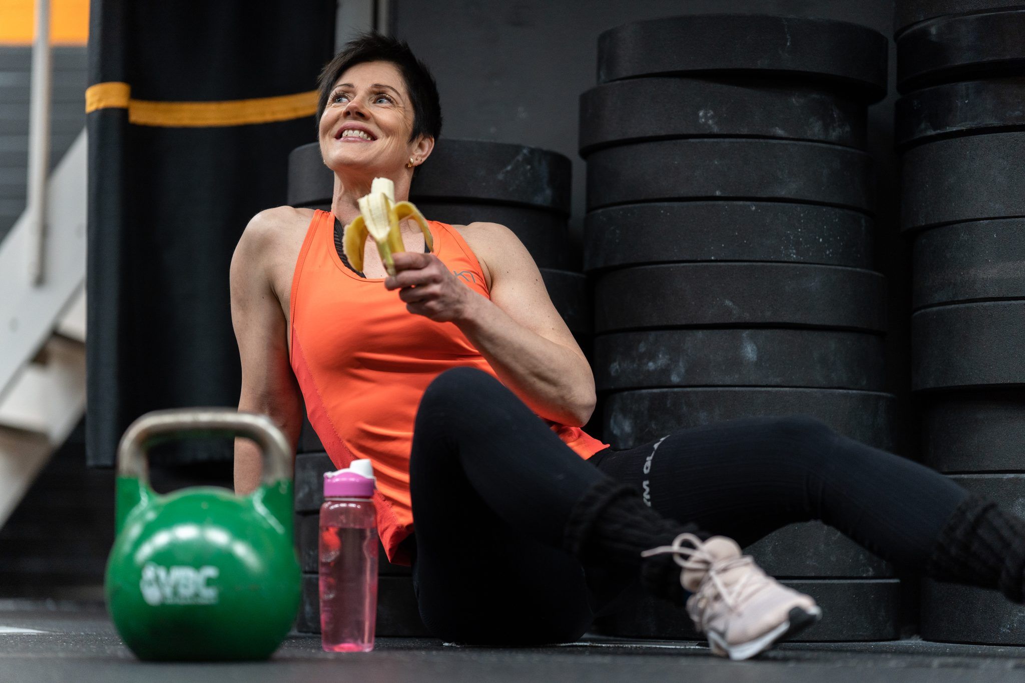 woman sitting at gym eating banana