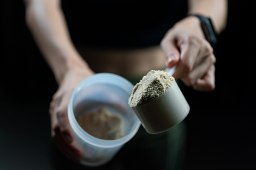 Person som häller proteinpulver i en shaker